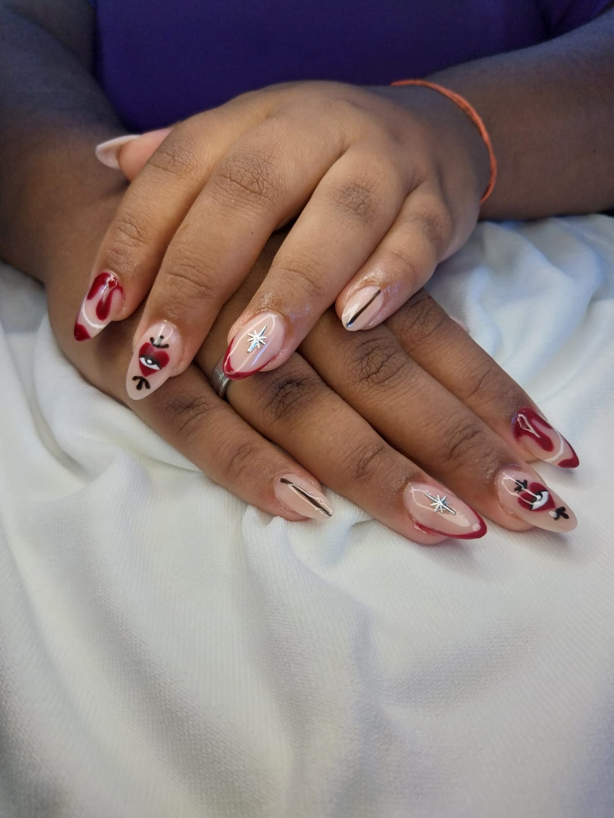 Unhas amendoadas com francesinha vermelha, corações e detalhes cromados
